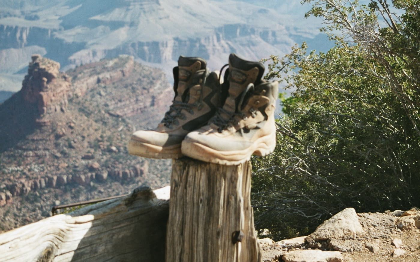 A pair of worn hiking boots on a post above a canyon