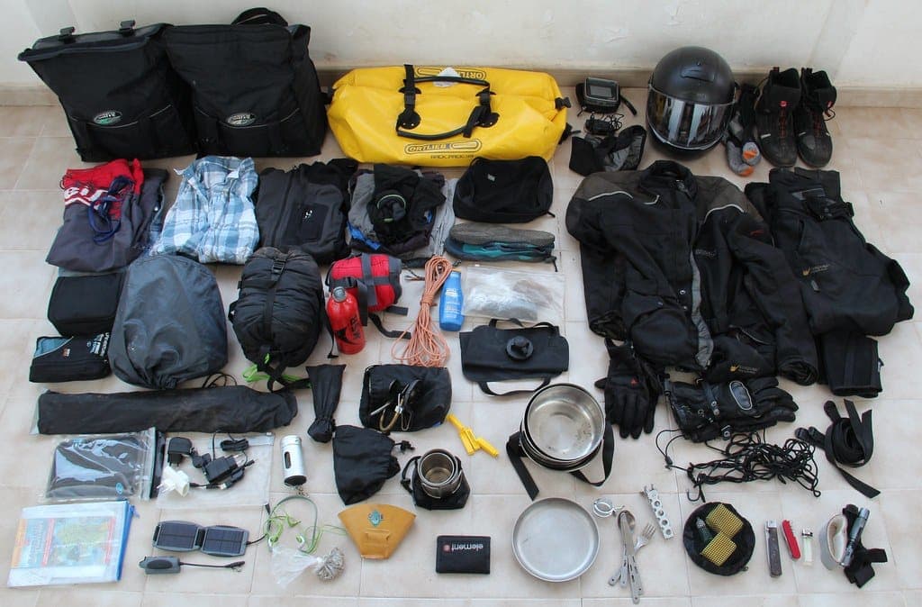 A rolled sleeping bag and camping gear laid out