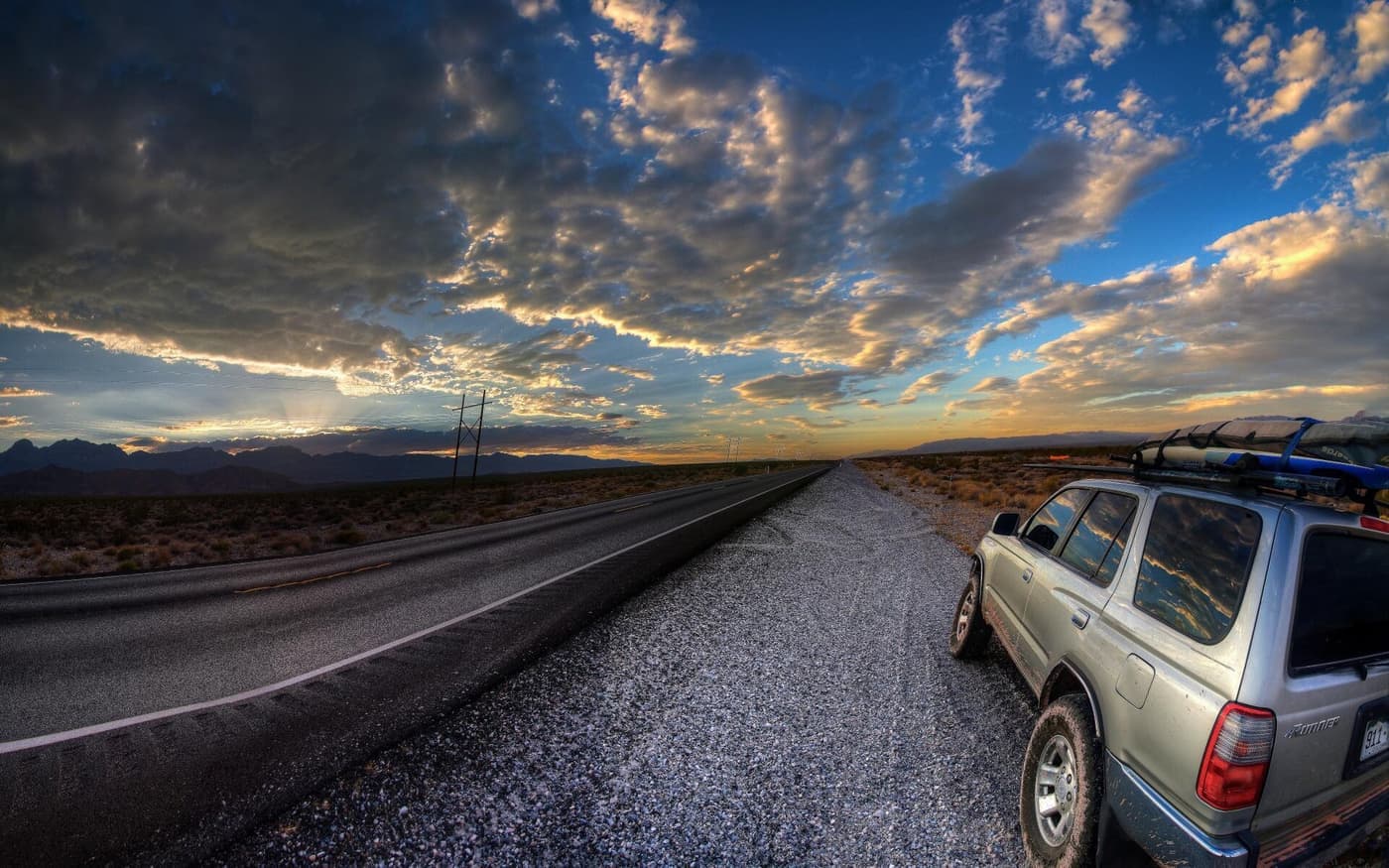 A loaded car on a road at sunset