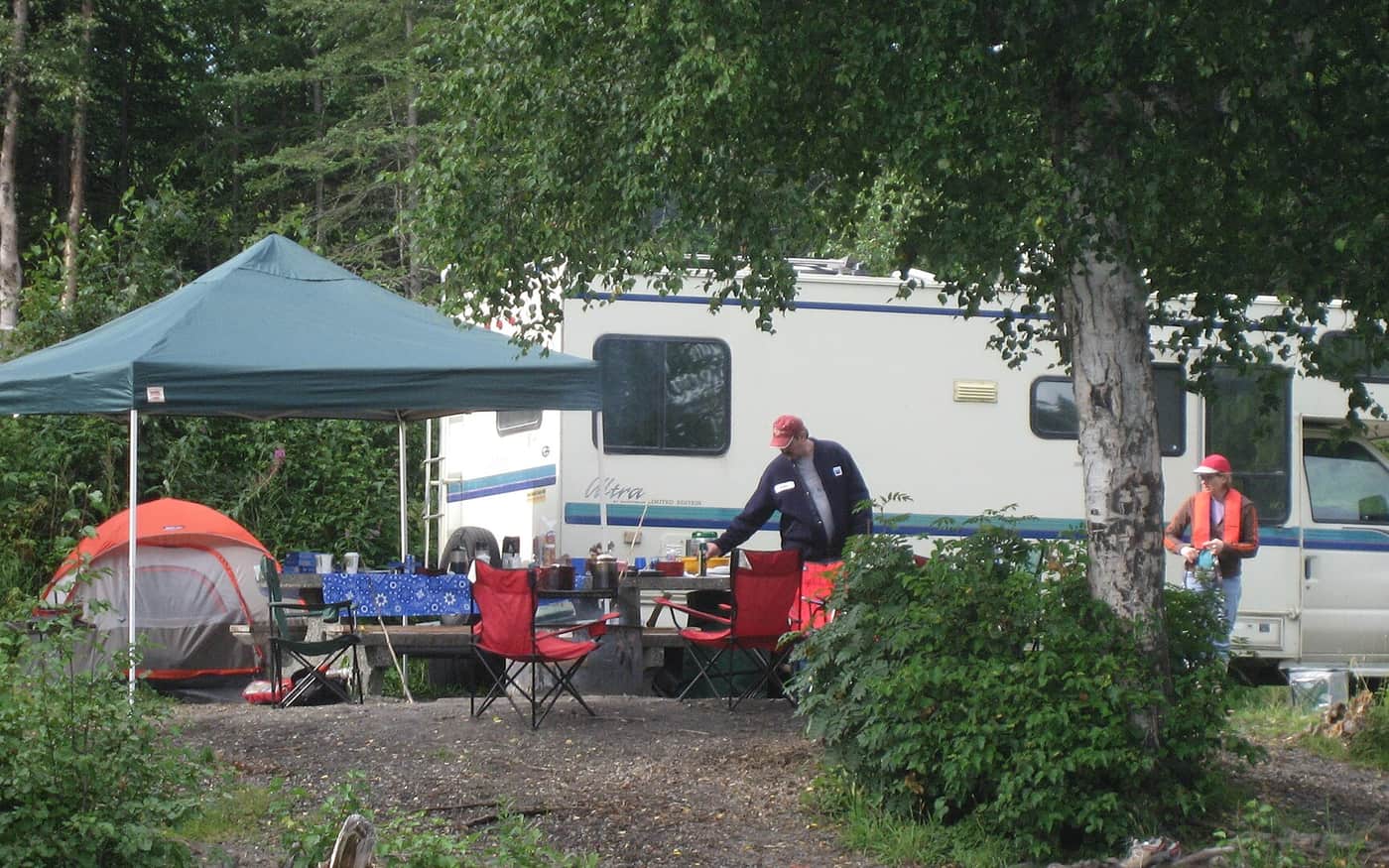 A campsite with a canopy, chairs, table and tent