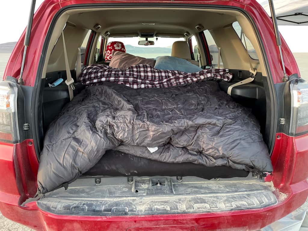 Camp bedding laid out in a vehicle sleeping setup