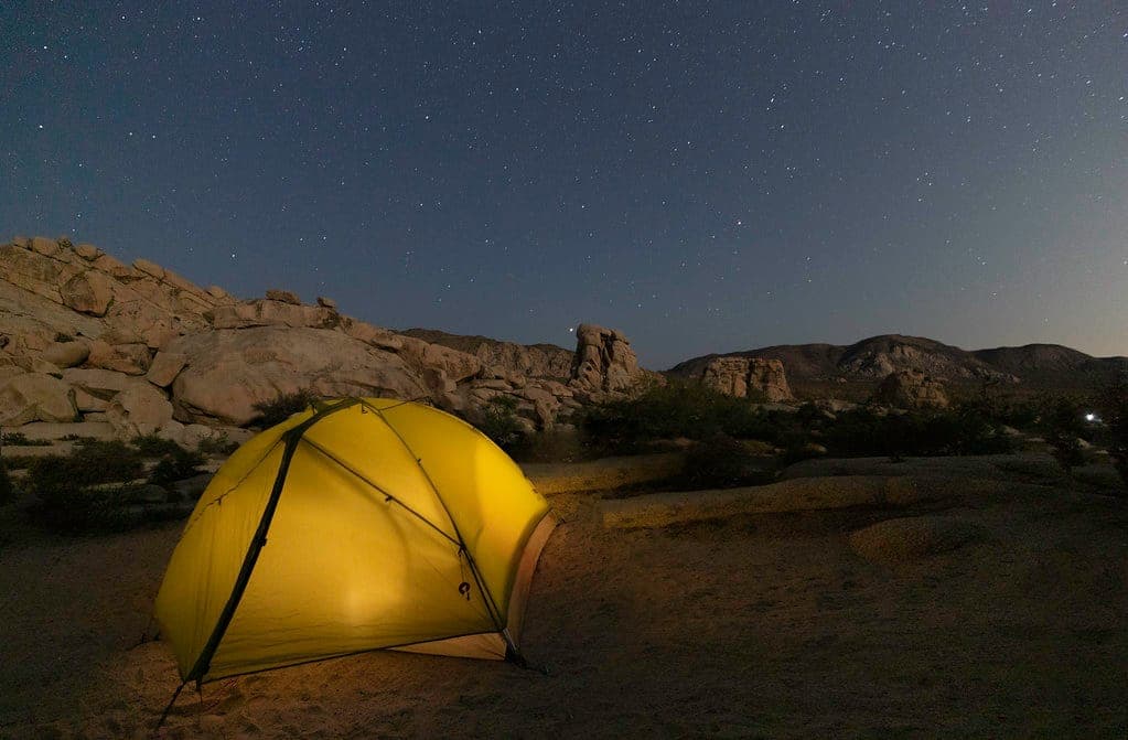 A tent lit from inside under a night sky